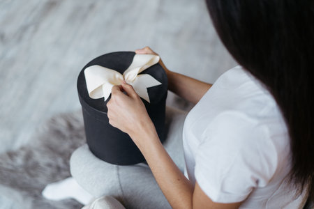 Cropped view of young adult woman holden wrapped gift in hands, unpacking present and spending free time at home with copy spaceの写真素材