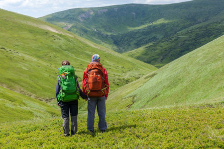 Back view of young adult traveller man holding hands with woman, standing together and looking at...