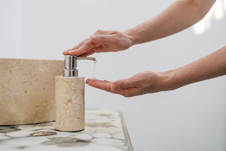 Cropped view of young adult girl washing hands, pump soap from bottle, making morning routine procedure and standing in bathroomの写真素材