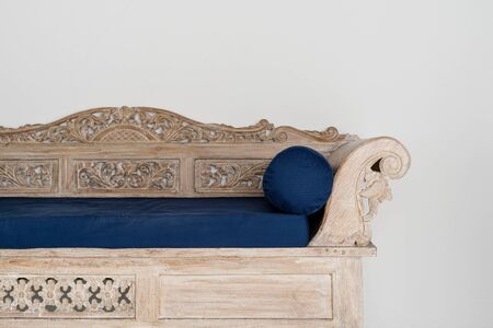 Wooden and carved couch with blue cushion near white wall in house with stylish traditional interior room and copy space  on backgroundの写真素材