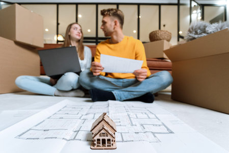 Selective focus on new house at architectural plan against blurred background with  young adult...