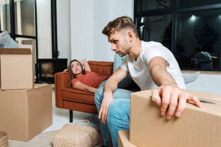 Exhausted and tired young adult husband move in new rent house together wife, resting on sofa at...