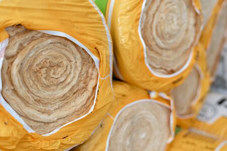 Selective focus on wrapped roll with mineral rockwool lying on attic floor inside house under constructionの写真素材
