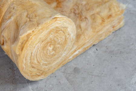 Roll of mineral rockwool lying on attic floor with copy space inside house under construction