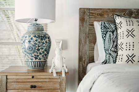 Close up of element white interior in cozy bedroom with comfort bed, lamp and rabbit toy on...