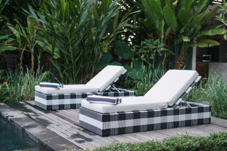 Swimming pool at spa resort with comfort lounge chair, towels and mattress on poolside with wooden...