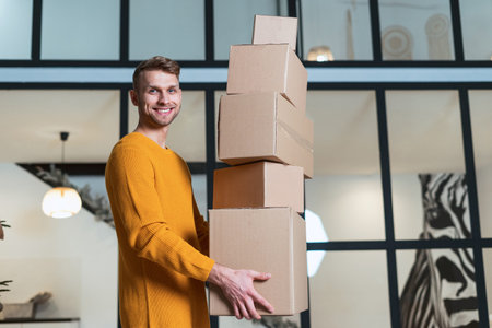 Relocation concept. Low angle view of happy and smiling young adult man move in new house, standing...