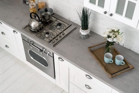 High angle photo of new kitchen with modern interior, furniture, gas stove, oven, wooden cabinets and breakfast tray on countertopの写真素材