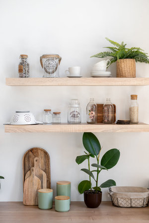 Vertical photo element of shelves in contemporary interior. Modern furniture on kitchen with kitchenware supplies, houseplants, cup, mug, cutting boards on wooden rackの写真素材