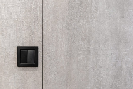 Element of modern interior design with black electric light switch on copy space, textured and grey...