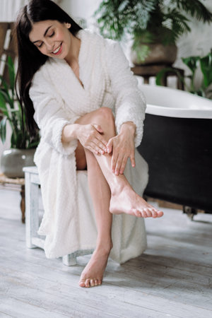 Happy young adult woman making massage, apply cream on skin, using organic cosmetic, skincare and...