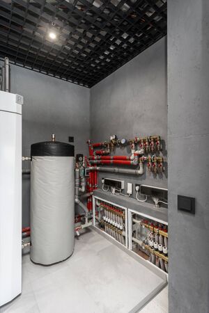 Vertical photo of technical boiler room in new modern house with filter on water tank capacity, pipes equipment, plumbing stuff and valves on electronic counter meterの写真素材