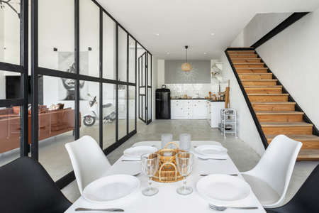 Modern house with contemporary dining room against kitchen drawers over cabinet, refrigerator and unestils. Table settings near living room at bringt apartmentの写真素材