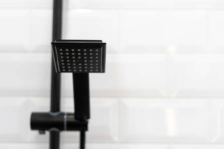 Modern apartment with white bathroom, black shower head on holder against tiled wall on copy space backgroundの写真素材