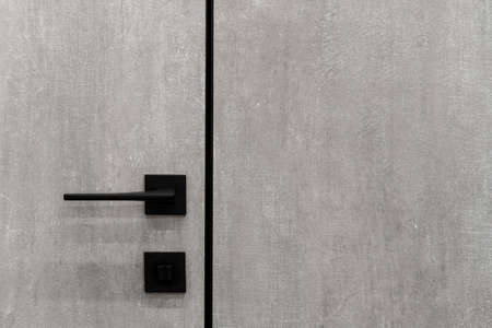 Close up of minimalist handle on closed grey door in house. Modern interior design with copy space wallの写真素材