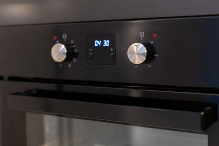Close up of built in appliance. Element of electric oven with timer and buttons on control panel in modern kitchen roomの写真素材
