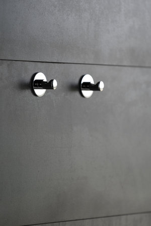 Vertical photo of two chrome towel hangers on tiles grey and copy space wall in contemporary...