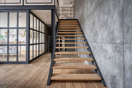 New wooden stairs in apartment house with modern interior design, near kitchen with glass wallの写真素材