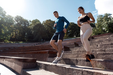 Fitness and healthy lifestyle concept. Low angle view of adult sportswoman and sportsman making...