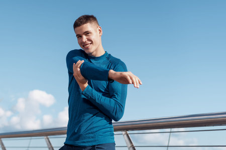 Concept of fitness activity in city. Smiling young sportsman making sport training outdoors alone,...