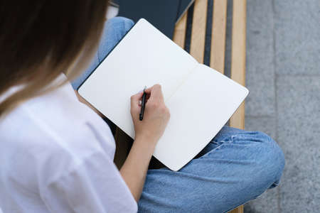 Education concept. Cropped pov of young high school student girl preparing homework project for lectures and optional subjects, writing at copy space pages copybookの写真素材