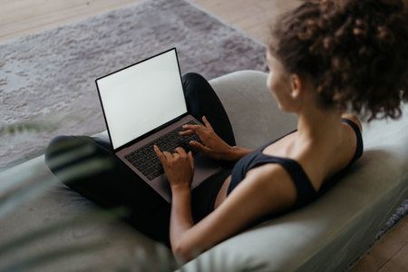 High angle view of young adult african american woman using modern laptop computer with copy space...