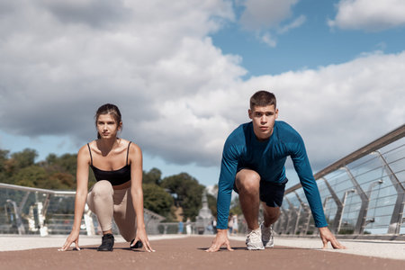 Focused young adult woman and serious man ready for competition. Friends making sport training...