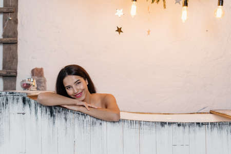 Smiling young adult girl taking bath, enjoying spa procedure, looking at camera and spending weekend at homeの写真素材
