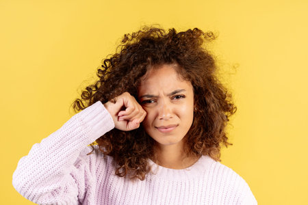 Portrait of sad and crying adult african american woman wipes away tears, looking at camera and...