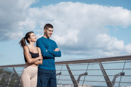 Happy adult sporty woman and smiling man looking aside crossed hands on chest, making sport training...