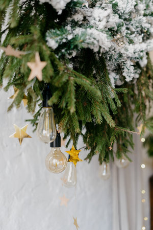 Element of winter style interior, garland lights on decorated new year tree and traditional decor at...