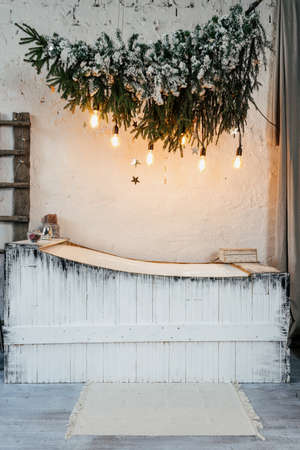 White cozy bathroom with winter style interior, decorated new year tree, garland lights and traditional december decor at homeの写真素材