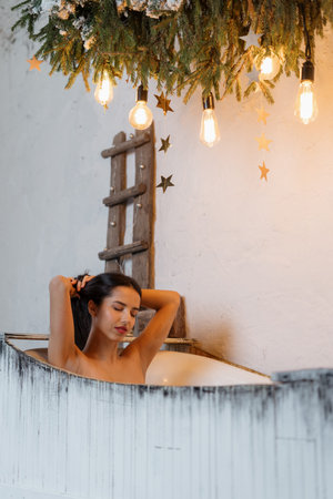Beautiful, dreamy young adult woman spending weekend at home, taking bath with closed eyes in cozy...