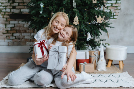 Merry christmas and happy new year. Caring and loving mother hugging her smiling daughter, holding...