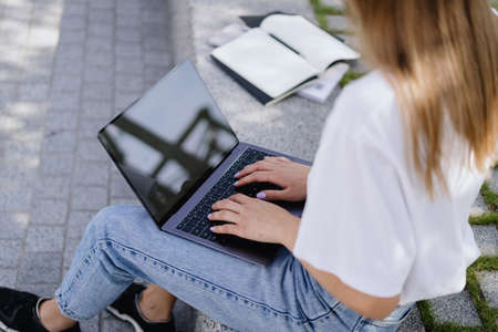 Remote and online education concept. Cropped pov of adult student girl using modern laptop computer with copy space and blank screen display, preparing homework exercise for lectures projectsの写真素材