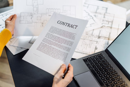 Cropped view of woman holding blueprint new house and contract, checking financial statistics data, analyzing real estate market, mortgage loan with low rate and construction investmentの写真素材