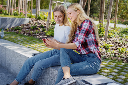 Internet addiction concept. Two happy adult student girl watching entertainment video and playing at...