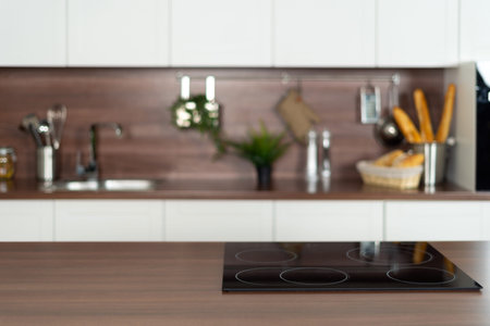 Panoramic view of wooden countertop with empty induction surface on ceramic glass stove against...