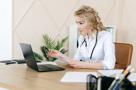 Concept of telemedicine and online consultation. Woman doctor in white uniform using laptop, talk...