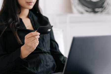 Young woman with credit card using modern laptop for shopping online, making transaction or charity...