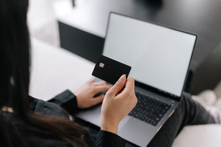 Ecommerce concept. Cropped shot of woman holding credit card doing online shopping on modern laptop...