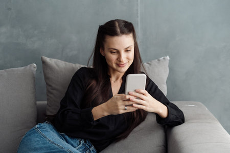 Young smiling woman using online app on her modern smartphone, send message, reading blog and...
