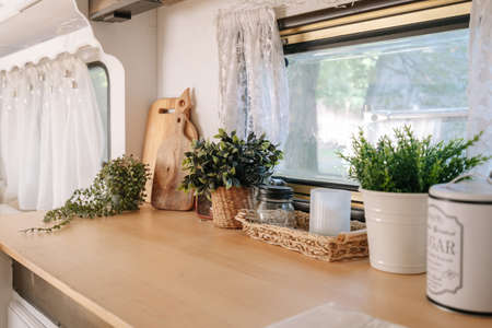 Interior of home, windowsill with flower, indoor camper van. Green plant near window, floral decor for house design. Houseplant nature in rv car, natural decoration in pot at wooden surface.の写真素材