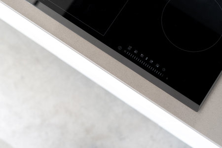 Integrated ceramic induction stove attached to kitchen counter, control panel with marked touch...