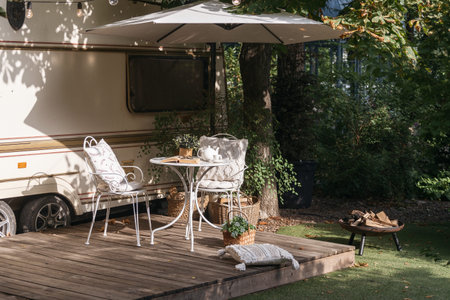 Camper van exterior, nobody near trailer house at nature. Cozy summer yard near rv park, terrace with outdoor furniture and decoration. Campsite near motorhome facade.の写真素材