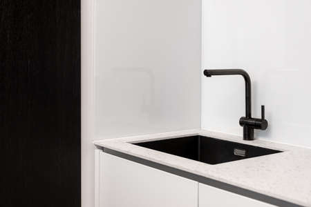 Kitchen interior, closeup at modern home design. Black sink at contemporary house room, clean steel faucet at white counter. Minimalistic apartment style with chrome domestic details.の写真素材