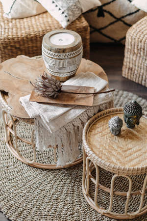High angle view of home decor, wicker furniture with natural materials stand in bright living room interior at bohemian style. Vertical shot of bamboo table, candle and dry flower in cozy apartmentの写真素材
