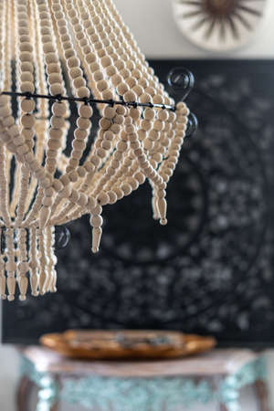Close up view of white wooden chandelier in boho chic style hanging in living room with blurred background. Vertical view of lightning equipment with natural materialsの写真素材