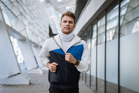 Healthy lifestyle concept. Young man running in the city. Athlete in sportswear warming up before every day workout. Healthy athlete or football player doing cardio exercise outdoorsの写真素材