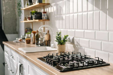 Side view of scandinavian style kitchen interior in white tones with stove, sink and shelves. Luxury apartment for sale. Cozy place for cooking conceptの写真素材